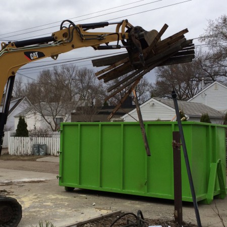 Backhoe loading rubbish wood and debris into a dumpster