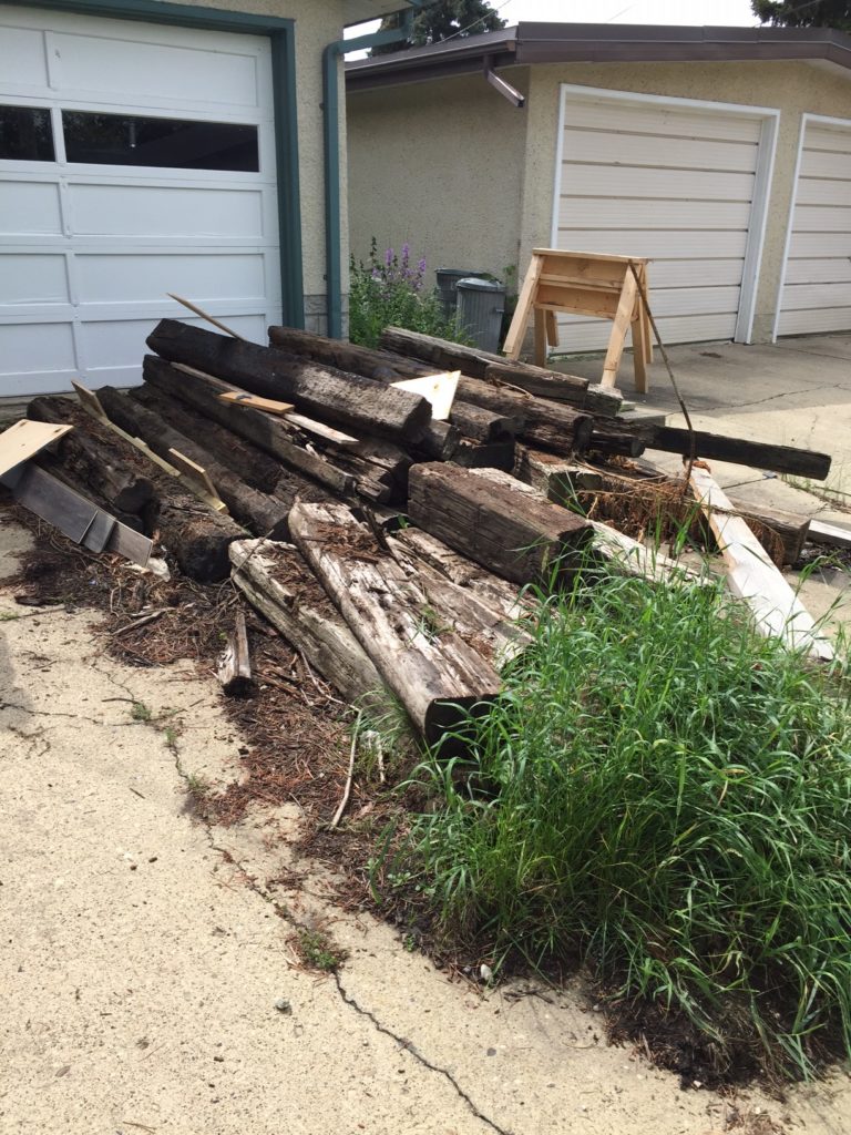 junk sitting on a driveway including railroad ties, wood and branches and other garbage in Edmonton