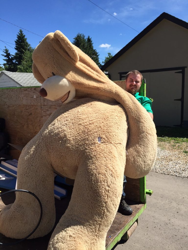 Our staff member holds a teddy bear that is twice his size found at a junk removal in Edmonton.