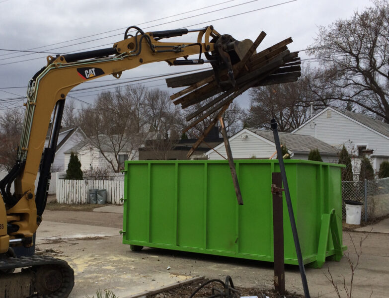 A backhoe loading construction debris into a container.